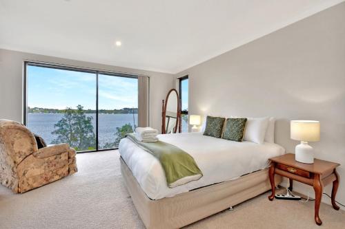 een slaapkamer met een bed en een stoel en een groot raam bij Lakeview Oasis with Panoramic Waterfront Views at Fishing Point in Fishing Point
