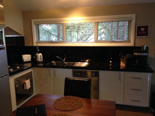 a kitchen with a sink and a window and a table at 3 Kings Bed and Breakfast in Yarra Junction