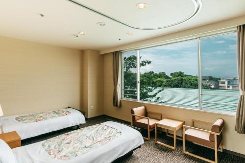 a hotel room with two beds and a window at KAMENOI HOTEL Yanagawa in Yanagawa