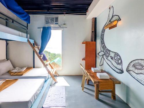 Zimmer mit 2 Etagenbetten und einem Tisch in der Unterkunft Lexias Hostel and Workspace - El Nido in El Nido