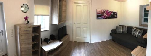 a living room with a couch and a clock on the wall at Haus am Eck - Gästehaus und Appartements in Altötting