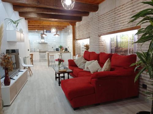 a living room with a red couch and a brick wall at Magia en el Arco in Olmedo