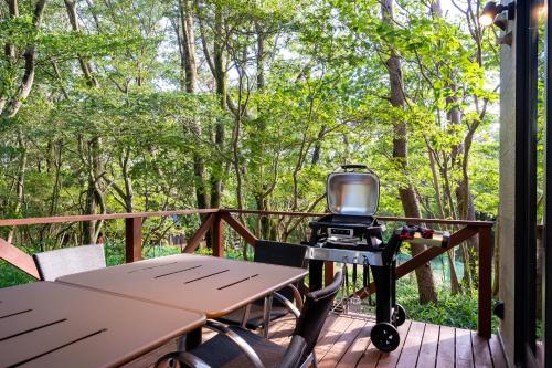 a grill on a deck with a table and chairs at Suite Villa Nasu Forest House in Nasu