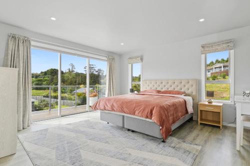 a white bedroom with a bed and a large window at Mandeno Magic - Kerikeri Holiday Home in Kerikeri