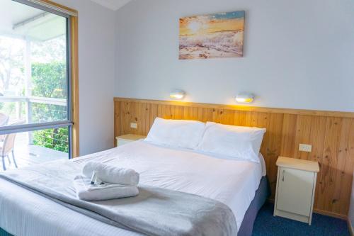 a bedroom with a large white bed and a window at Thou Walla Sunset Retreat in Soldiers Point