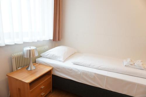a small bedroom with a bed and a night stand at Hotel Kaffeemühle in Vienna