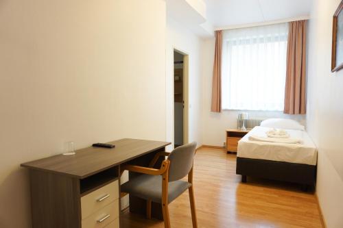 a bedroom with a desk and a bed with a window at Hotel Kaffeemühle in Vienna