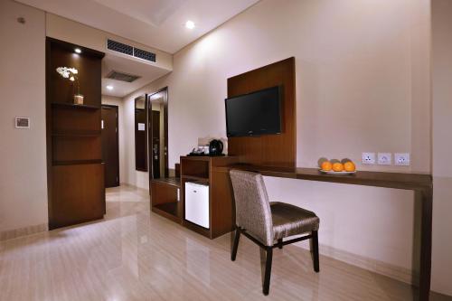 a room with a bar with a chair and a television at Aston Imperial Bekasi Hotel & Conference Center in Bekasi