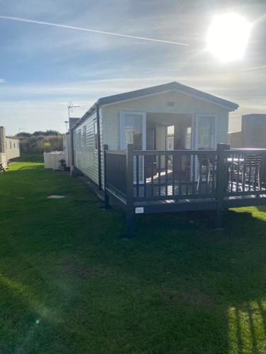 a small house with a porch on a lawn at Modern 3 bedroom caravan near the beach in Walton-on-the-Naze