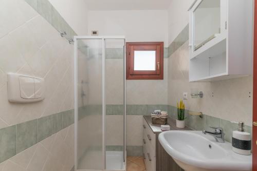 a bathroom with a sink and a glass shower at Olbia Mare Apartment in Olbia