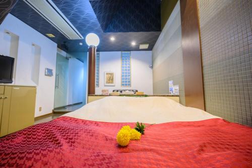 a room with a bed with a red blanket and yellow flowers at BLAN VILLA 旧bibi in Kashiba