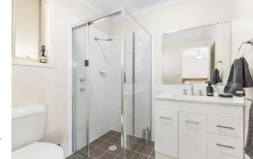 a white bathroom with a shower and a sink at Hunter Home with POOL / CINEMA ROOM / PING PONG in Cessnock