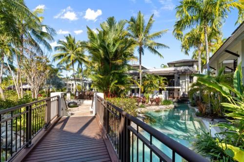 a walkway leading to a resort with a pool and palm trees at Temple Resort & Spa Port Douglas in Port Douglas