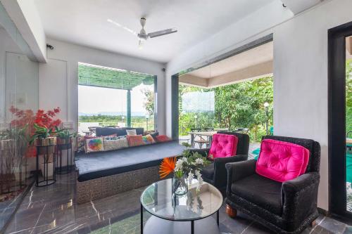 a living room with a couch and chairs and a table at StayVista's Vine & Splash - Riverside villa with an infinity pool and indoor games in Karjat