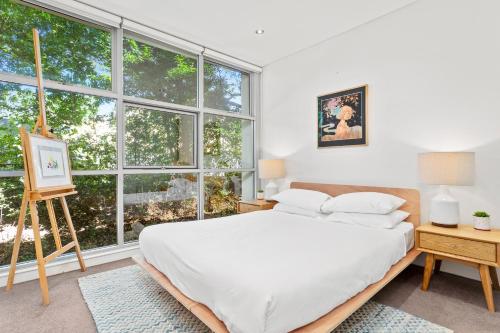 een slaapkamer met een bed en een groot raam bij Charming Modern Apartment with City Views DUPLICATE in Sydney