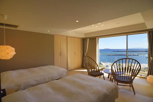 a hotel room with two beds and a table and chairs at Atami Seaside Spa & Resort in Atami