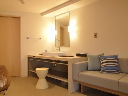 a bathroom with a sink and a couch and a mirror at Atami Seaside Spa & Resort in Atami