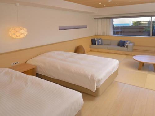 a hotel room with two beds and a couch at Atami Seaside Spa & Resort in Atami