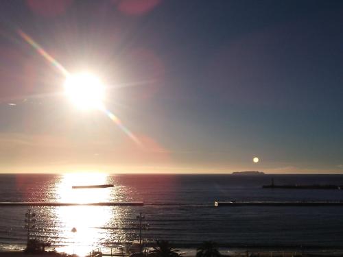 a sun is setting over the ocean with the ocean gmaxwell at Atami Seaside Spa & Resort in Atami