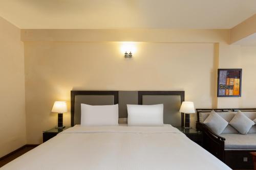 a bedroom with a large white bed with two lamps at The Oasis Mussoorie - A Member of Radisson Individuals in Mussoorie