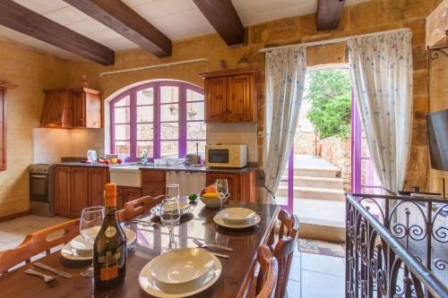 een keuken met een tafel en een fles wijn bij Gozitan Farmhouse with Pool - PP 1 in Il-Wilġa