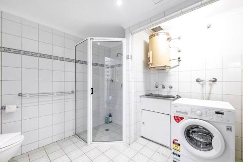 y baño con lavadora y ducha. en Cullen Bay Penthouse with Pool, Decks and Marina Views, en Larrakeyah