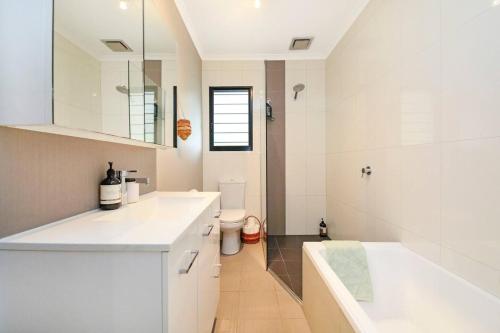 La salle de bains blanche est pourvue d'un lavabo et de toilettes. dans l'établissement A Tropical Pool Paradise in Rapid Creek, à Nightcliff