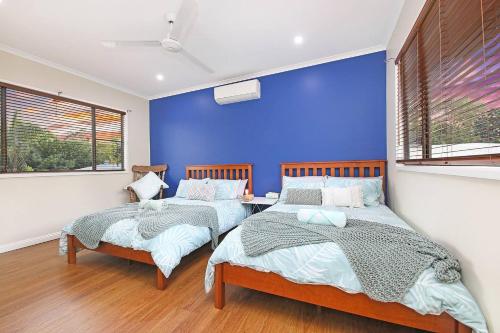 2 camas en una habitación con una pared azul en A Tropical Pool Paradise in Rapid Creek, en Nightcliff