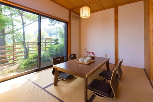 a dining room with a table and chairs and a large window at Suite Villa Ocean View Atami Shizenkyo in Atami