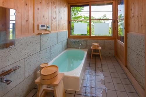 スイートヴィラ オーシャンビュー熱海⾃然郷 في أتامي: حمام مع حوض استحمام و كرسيين