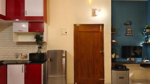 a kitchen with a refrigerator and a wooden door at 2390 Home Tales by Tipiverse, HSR Layout in Bengaluru