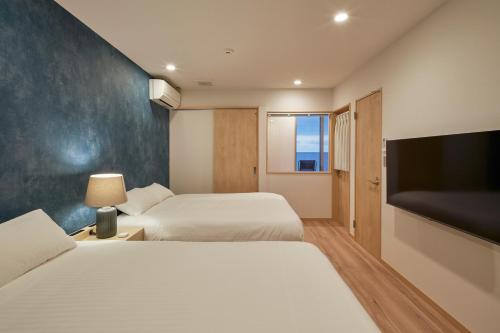 um quarto de hotel com duas camas e uma televisão de ecrã plano em ALFACIO RESORT STAY ITOSHIMA em Itoshima