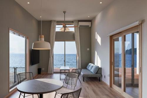 a living room with a table and chairs and the ocean at ALFACIO RESORT STAY ITOSHIMA in Itoshima