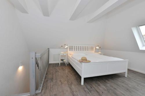ein weißes Schlafzimmer mit einem weißen Bett und einer Treppe in der Unterkunft STöRTEBEKER APPARTEMENTS - "BLAUES HAUS" in Ralswiek
