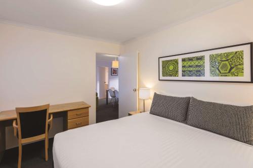 um quarto com uma cama branca e uma secretária. em Adina Serviced Apartments Canberra Kingston em Camberra