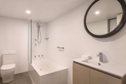 uma casa de banho com um lavatório, WC e um espelho. em Adina Serviced Apartments Canberra Kingston em Canberra