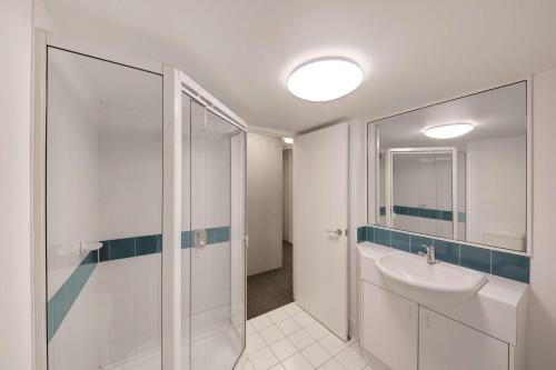 a white bathroom with a sink and a shower at Adina Serviced Apartments Canberra James Court in Canberra