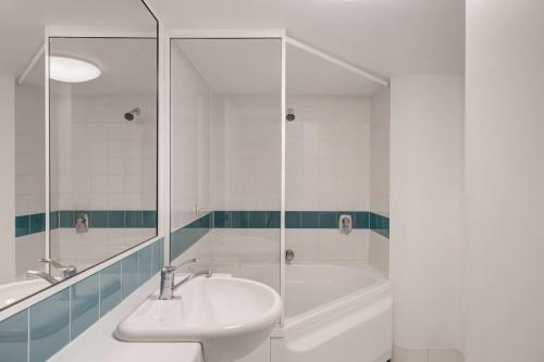 a bathroom with a tub and a sink and a shower at Adina Serviced Apartments Canberra James Court in Canberra