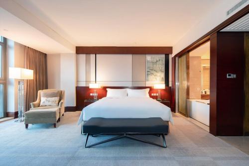a hotel room with a bed and a chair at Marco Polo Jin Jiang in Jinjiang