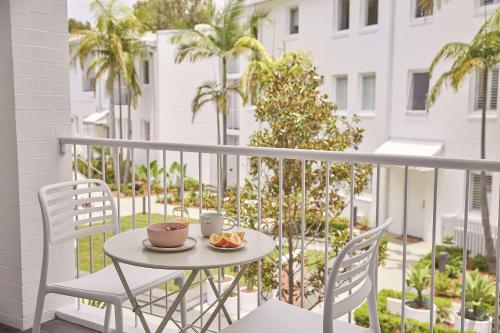 a table with two chairs and a cup of coffee on a balcony at Adina Apartment Hotel Chippendale in Sydney