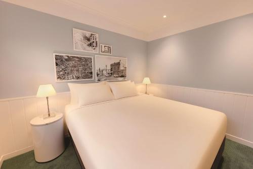 a bedroom with a large white bed and a lamp at Adina Apartment Hotel Chippendale in Sydney