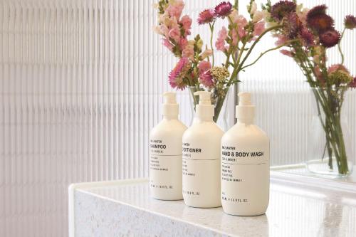 a group of three bottles sitting on a table with flowers at Adina Apartment Hotel Chippendale in Sydney