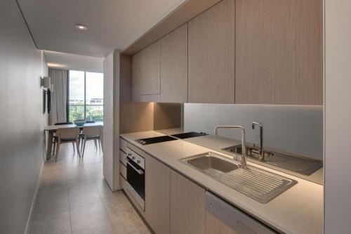 a kitchen with wooden cabinets and a sink and a table at Adina Apartment Hotel Bondi Beach Sydney in Sydney