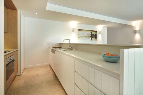 uma cozinha com armários brancos e uma tigela azul no balcão em Adina Apartment Hotel Bondi Beach Sydney em Sydney