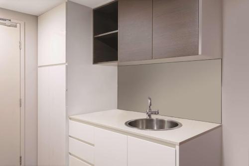 uma cozinha branca com um lavatório e armários em Adina Apartment Hotel Darwin Waterfront em Darwin