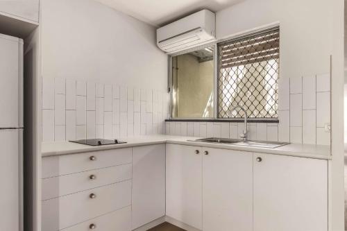 a white kitchen with two sinks and a window at Travelodge Resort Darwin in Darwin