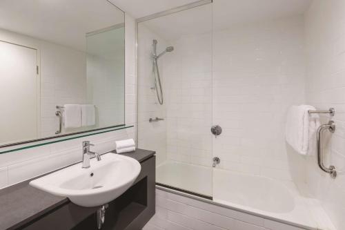 a bathroom with a sink, mirror, and bathtub at Vibe Hotel Darwin Waterfront in Darwin