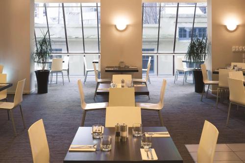 a dining room with tables and chairs and windows at Travelodge Hotel Wellington in Wellington