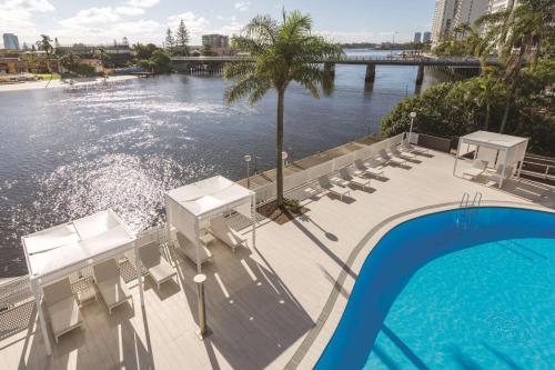 einen Pool mit Stühlen und Blick auf das Wasser in der Unterkunft Vibe Hotel Gold Coast in Gold Coast