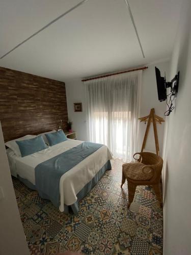 a bedroom with a bed and a chair and a window at HOSTAL LA BATUTA in Mogente